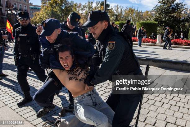 Police restrain a FEMEN activist with body paint during a counterprotest before the start of a rally commemorating the 47th anniversary of Spain's...