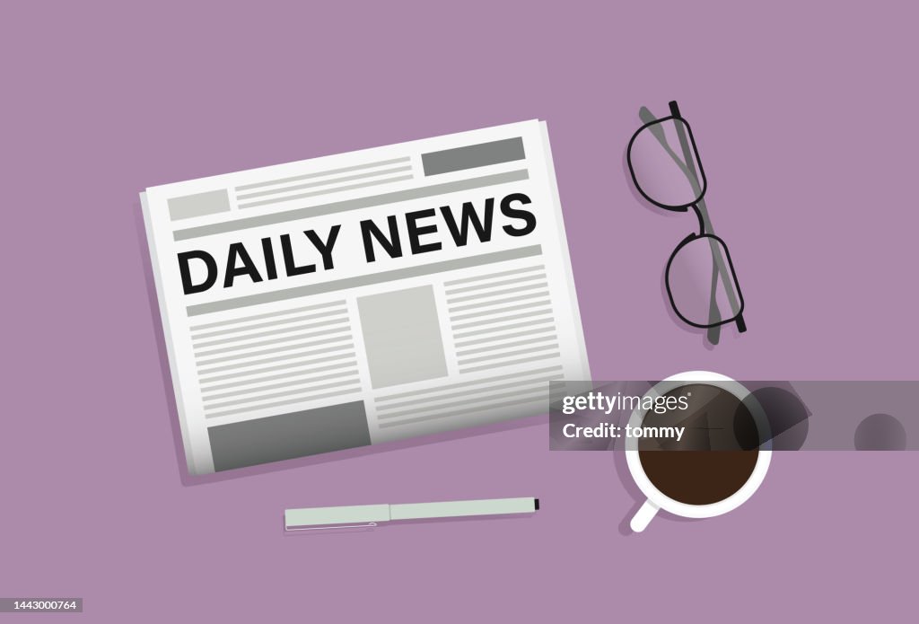 Zeitung, Brille, Stift und Kaffeetasse auf dem Tisch