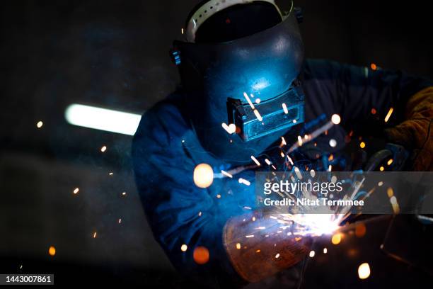 labor skill is the driver in the construction industry. front view of african american welder working in a metal manufacturing facility to build structures, equipment, and construction metal components. - blacksmith sparks stock-fotos und bilder