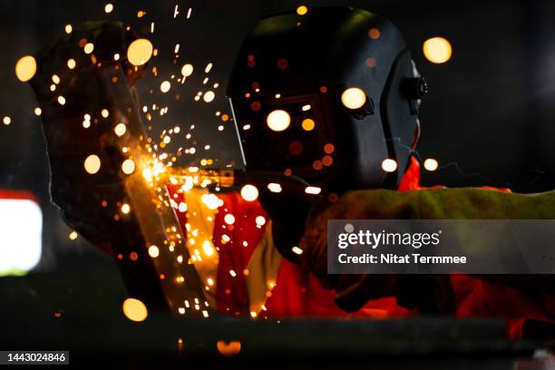 safety first in welding operations.  an african american industrial welder working welding metal seams of a construction beam in a metal plant wearing a protective mask to protect sparks on a metal work welding. - fonderie photos et images de collection