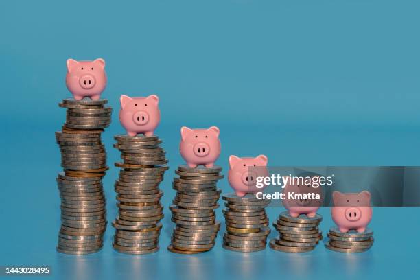 piggy banks standing on top of stacks coins. - conta bancária - fotografias e filmes do acervo