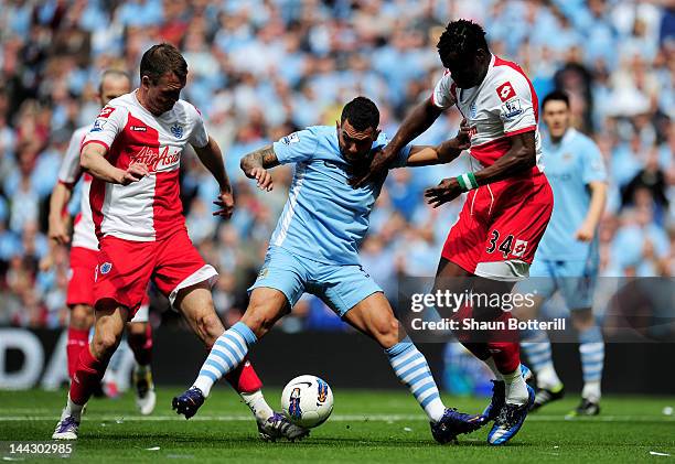 Carlos Tevez of Manchester City is challenged by Clint Hill and Taye Taiwo of QPR during the Barclays Premier League match between Manchester City...