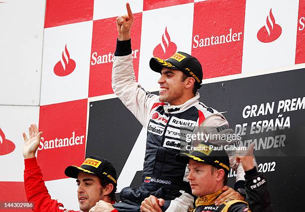 Race winner Pastor Maldonado of Venezuela and Williams celebrates on the shoulders of second placed Fernando Alonso of Spain and Ferrari and third...