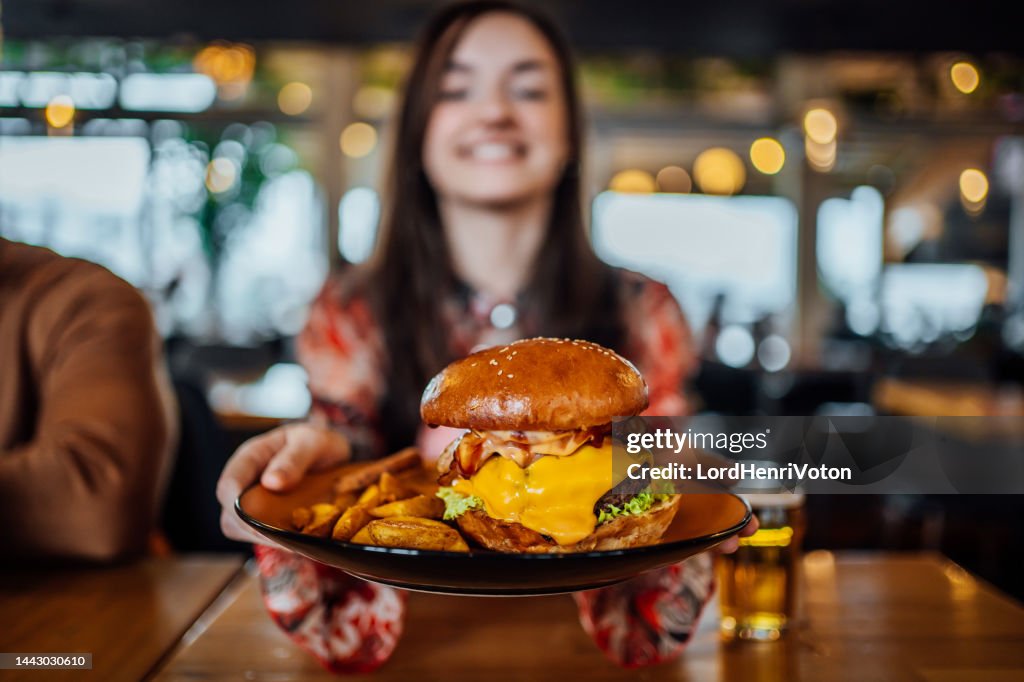 Young woman holding a plate with a tasty burger