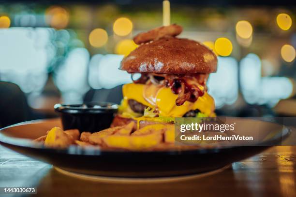 burger in bun with cheese and vegetable garnish - comida de pub imagens e fotografias de stock