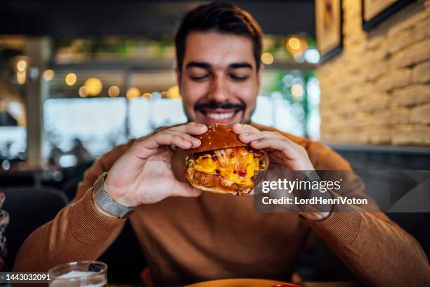 ハンバーガーを食べる準備ができている若い男 - 盛り付け 手 ストックフォトと画像