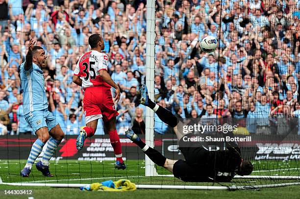 Carlos Tevez of Manchester City celebrates as the shot from teammate Pablo Zabaleta beats goalkeeper Paddy Kenny of QPR for the opening goal during...