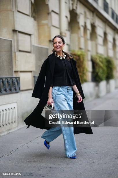 Alba Garavito Torre wears gold large and white pendant earrings, a gold large chain with white large pearls necklace, a black tweed jacket, a black...