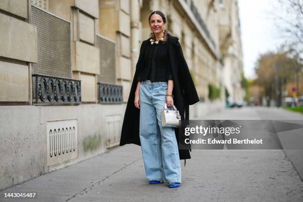 Alba Garavito Torre wears gold large and white pendant earrings, a gold large chain with white large pearls necklace, a black tweed jacket, a black...