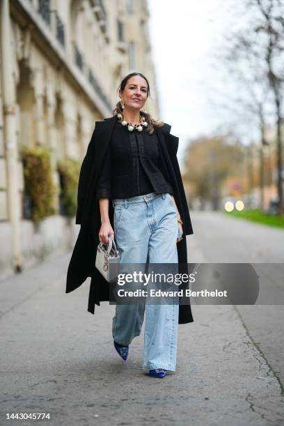 Alba Garavito Torre wears gold large and white pendant earrings, a gold large chain with white large pearls necklace, a black tweed jacket, a black...