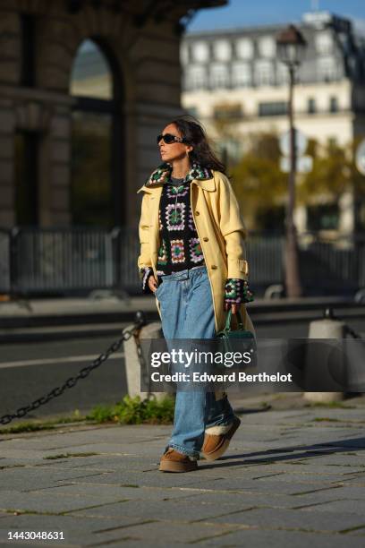 Gabriella Berdugo wears black sunglasses from Versace, gold earrings, a black / brown / green / purple / white print pattern puffy wool / zipper...