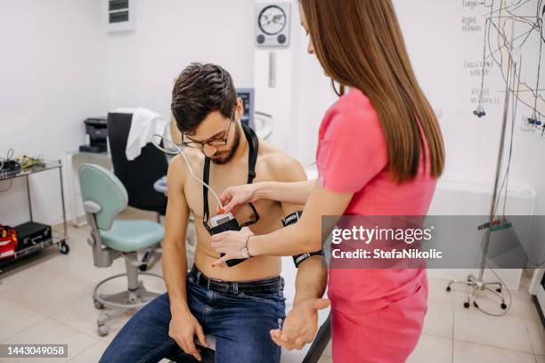 doctor puts a holter on a man's chest - stress test stockfoto's en -beelden