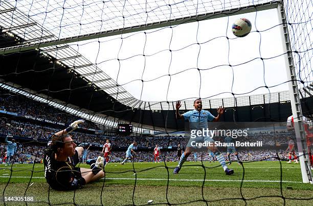 Carlos Tevez of Manchester City celebrates as the shot from teammate Pablo Zabaleta beats goalkeeper Paddy Kenny of QPR for the opening goal during...