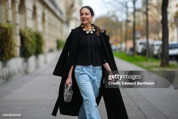 Alba Garavito Torre wears gold large and white pendant earrings, a gold large chain with white large pearls necklace, a black tweed jacket, a black...