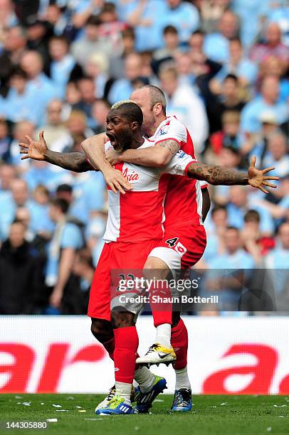 Djibril Cisse of QPR celebrates with teammate Shaun Derry after scoring his team's first goal during the Barclays Premier League match between...