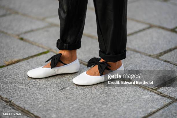 Gabriella Berdugo wears black shiny leather large pants Barbara Bui, white leather ballerinas with black knot on the toe cap, during a street style...