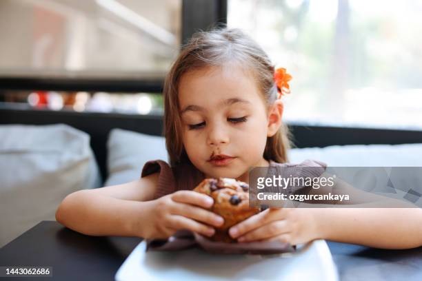 kleine süße mädchen essen ungesunde schokolade cupcake - cupcakes girls stock-fotos und bilder