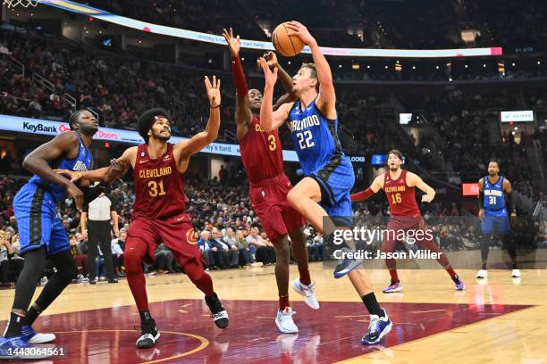 Franz Wagner of the Orlando Magic shoots over Caris LeVert and Jarrett Allen of the Cleveland Cavaliers during the first half at Rocket Mortgage...