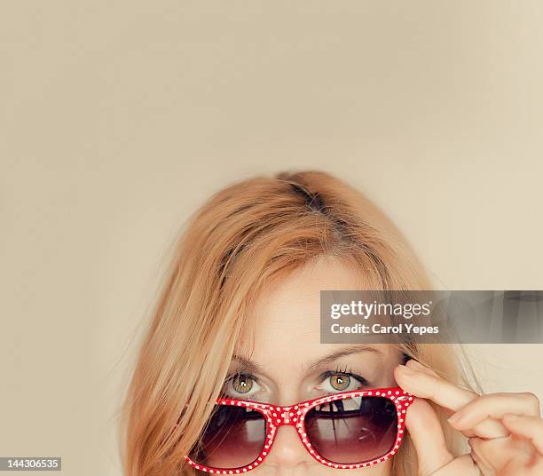 blonde woman with red glasses - regarder à la dérobée photos et images de collection