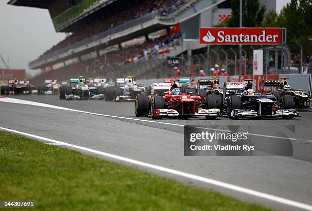 Pastor Maldonado of Venezuela and Williams and Fernando Alonso of Spain and Ferrari drive side by side after the start of the Spanish Formula One...