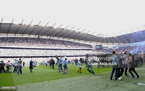 Manchester City's supporters celebrate on the pitch after their team's 3-2 victory over Queens Park Rangers in the English Premier League football...