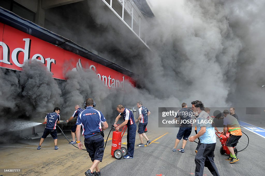 Racing team crews try to extinguish a fi