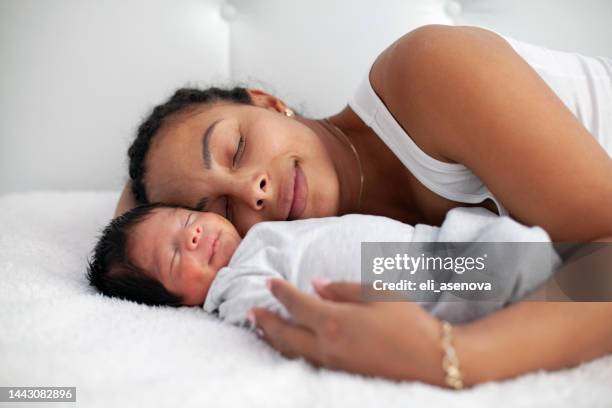 african-american mother having fun with cute baby boy on the bed - baby close up bed stockfoto's en -beelden