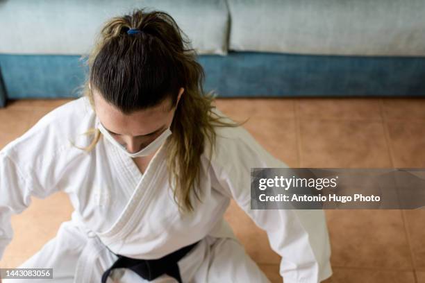 blonde girl in a mask practicing karate at home. karate black belt. quarantine virus. home isolated. - karate girl isolated stock pictures, royalty-free photos & images