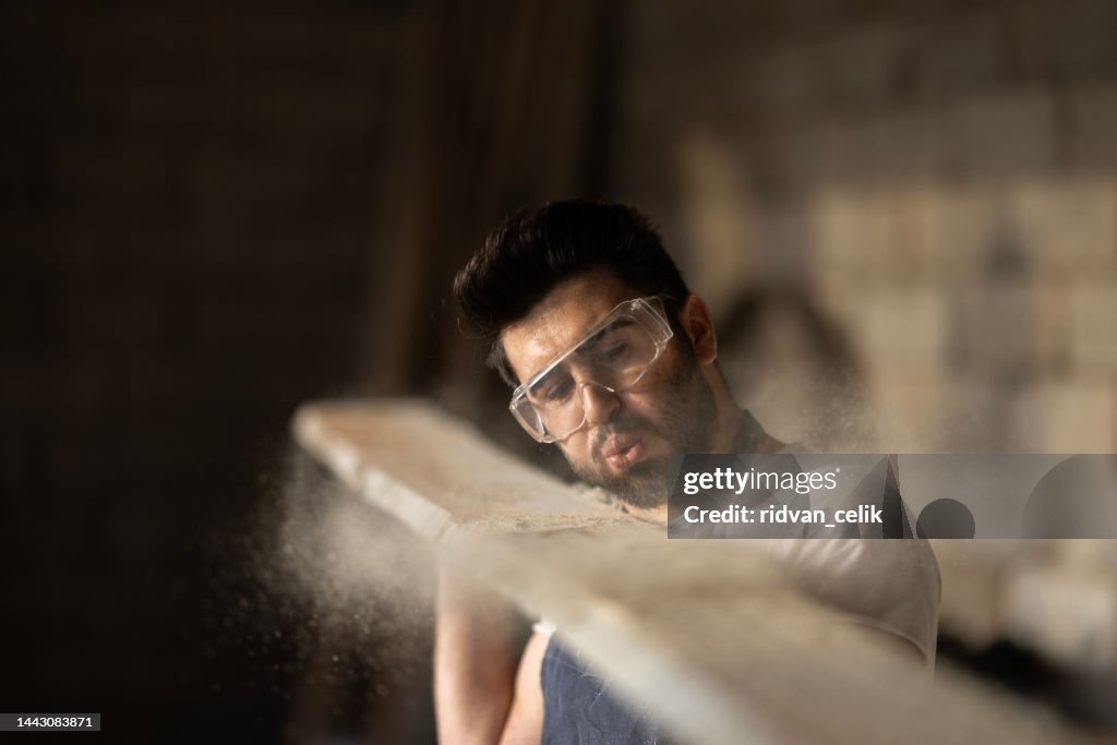 Manual Worker Blowing Sawdust From A Wood At Carpentry Workshop High ...