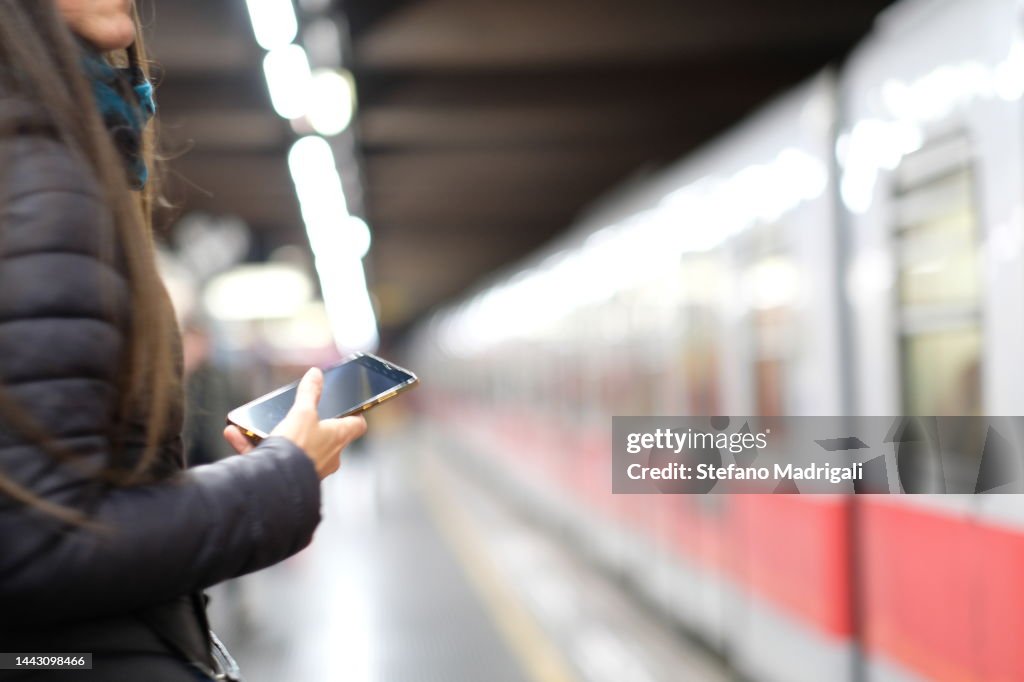 Girl with smartphone as the train arrives on the subway