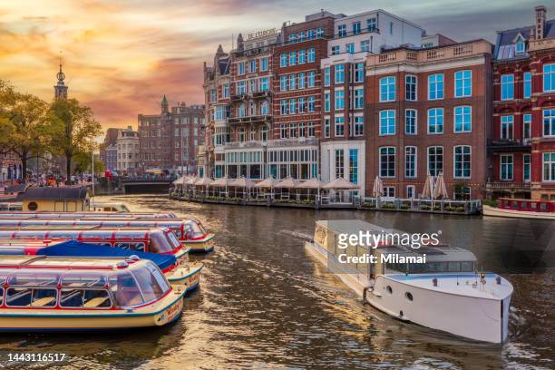 hotel de l’europe, iconic amsterdam landmark. the river amstel during sunset. netherlands. - fluss amstel stock-fotos und bilder