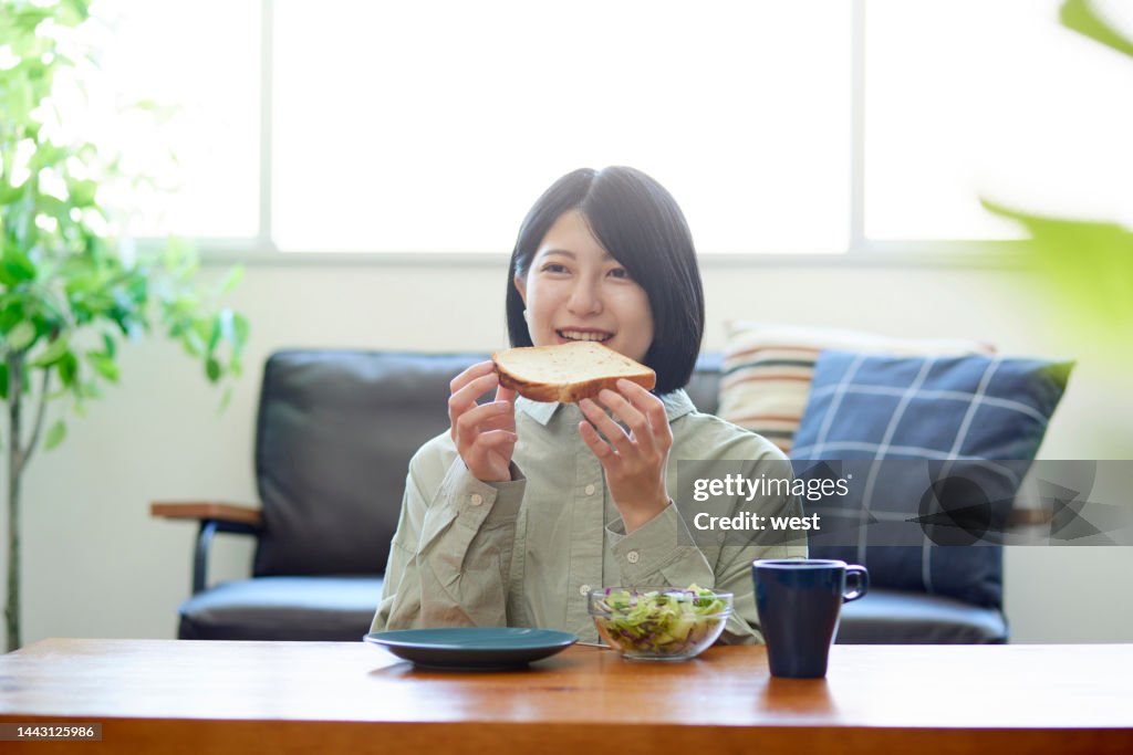 Young Japanese woman eating breakfast in the living room