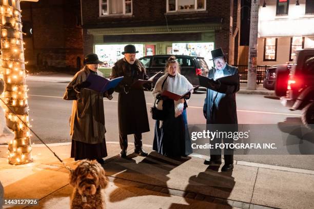 mature people singing christmas carols outdoors at night - carol singer stock pictures, royalty-free photos & images