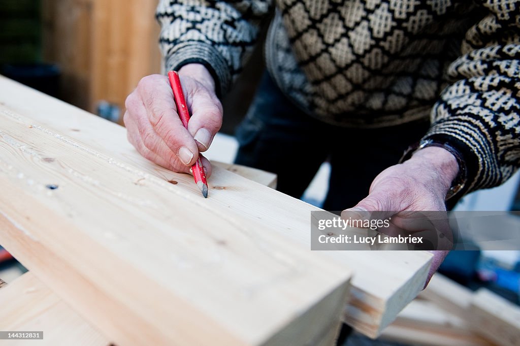 Carpenter marking wood with pencil
