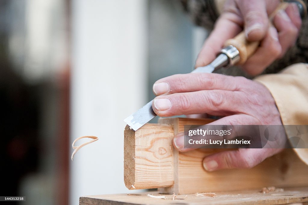 Carpenter carving wood with  chisel