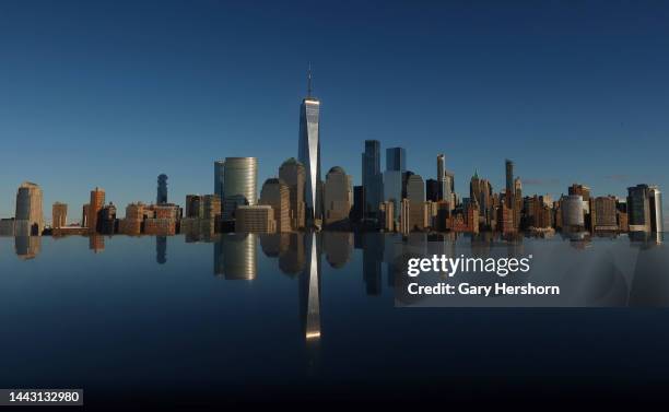 The skyline of lower Manhattan and One World Trade Center in New York City is reflected on the top of a monument along the Hudson River on November...