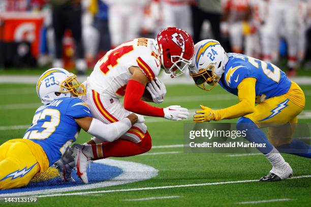 Skyy Moore of the Kansas City Chiefs is tackled by Nasir Adderley and Bryce Callahan of the Los Angeles Chargers during the first quarter at SoFi...