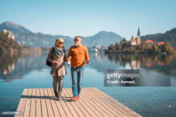 passeggiata della domenica mattina per una coppia di anziani al lago alpino - lago di bled foto e immagini stock