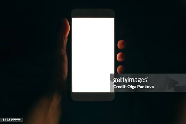 phone with white screen in human hand in the dark - telegram stockfoto's en -beelden