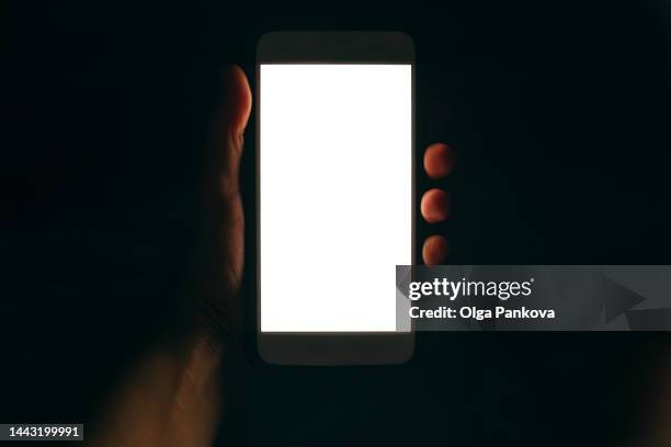 phone with white screen in human hand in the dark - social influencer stock pictures, royalty-free photos & images