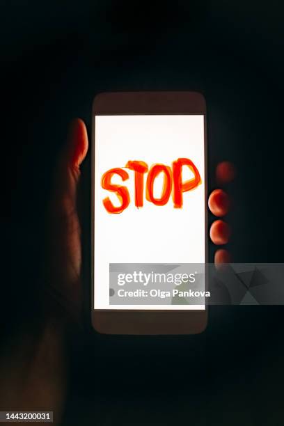 human hand holds phone with the word "stop" - stop enkel woord stockfoto's en -beelden