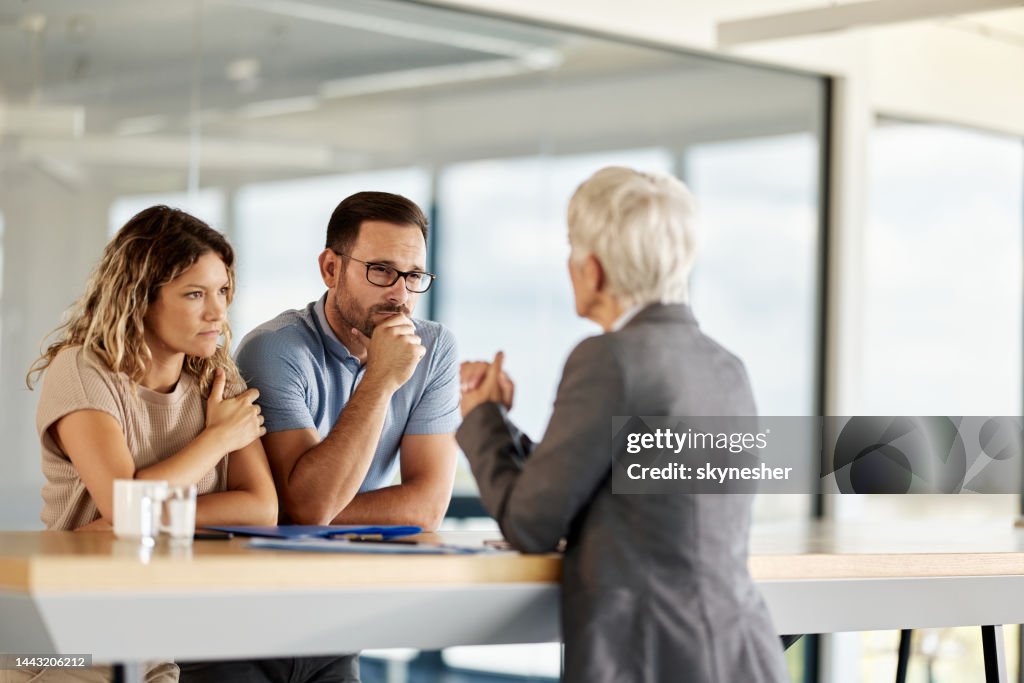Young couple listening to insurance agent in the office.