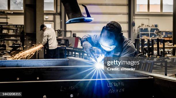 soldador trabajando en fábrica - soldar fotografías e imágenes de stock