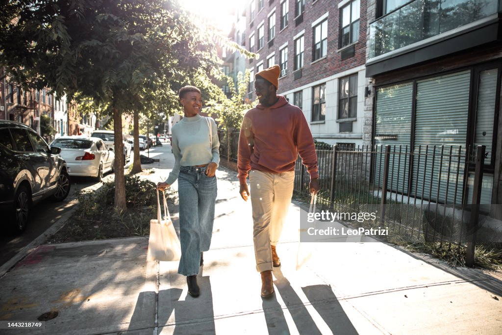 Couple walk back home in the streets in Bushwick - Brooklyn NY with reusable shopping bags