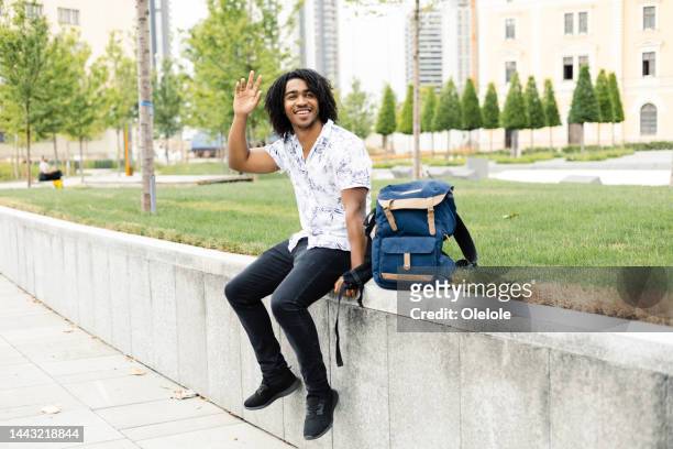 portrait of a happy student greeting someone on the street - curly waves stock pictures, royalty-free photos & images