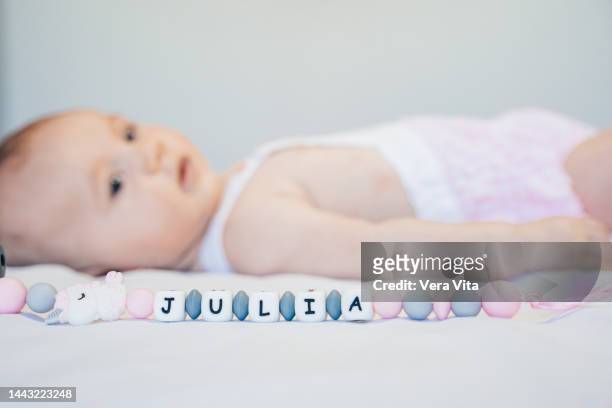 selective focus on newborn baby name on pacifier with baby in background. - naamplaatje etiket stockfoto's en -beelden