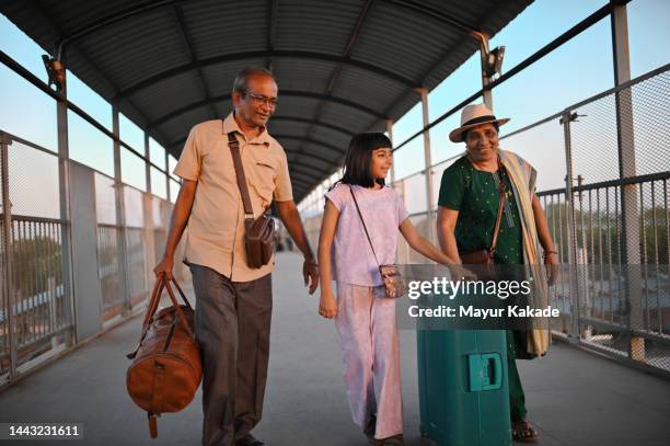 cute girl walking with her grandparents on a railway bridge with their travel bag - india travel stock pictures, royalty-free photos & images