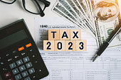 Tax text in wooden cubes and tax or vat form documents to complete Individual income tax return form for payment to Government. Calculation tax return in 2022 to 2023.