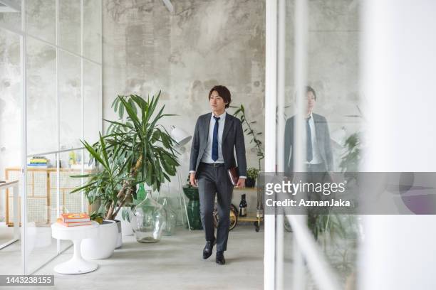 portrait of a confident japanese ceo walking in the office - walking away from camera stock pictures, royalty-free photos & images