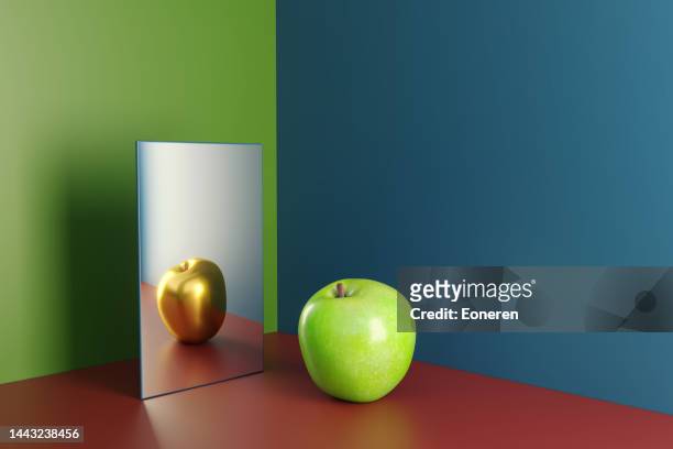 ein grüner apfel im spiegel, der die goldene version seiner selbst reflektiert - distorted image stock-fotos und bilder